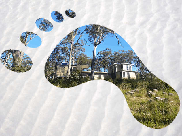 Image of sustainable house seen through a footprint in the sand.
