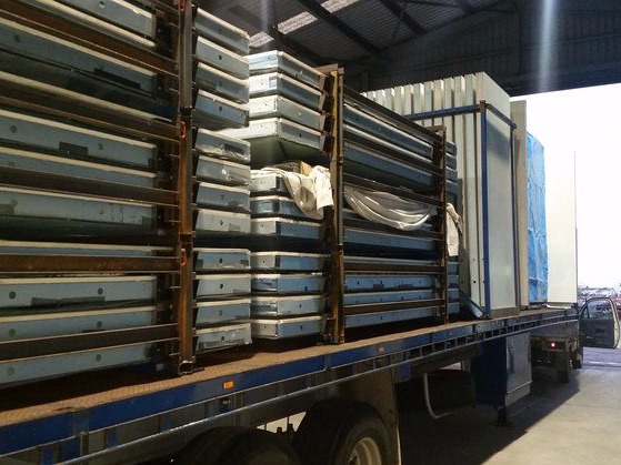 A truck trailer is neatly stacked with MAAP House panels ready for delivery